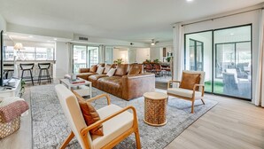 Un salón espacioso con sofá, sillones y una zona de comedor al fondo.