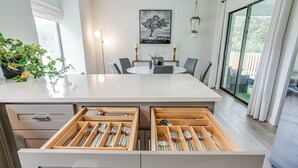 Una cocina moderna con una isla central, cajones de madera y una zona de comedor con mesa y sillas.