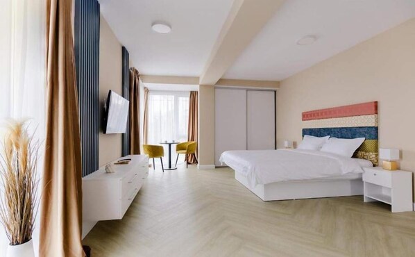 Relax in a serene space with a large bed, flat-screen TV, and comfortable desk area.