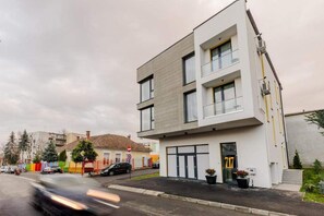 Stylish two-story building with a flat facade and large windows, featuring a balcony and a black door.