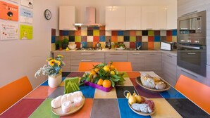 A modern kitchen with a colorful backsplash, stainless steel appliances, and a dining area with a table set for a meal. - YourHome - Karme House (Meta)