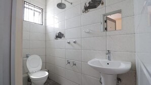 Een badkamer met toilet, wastafel, douche en spiegel.