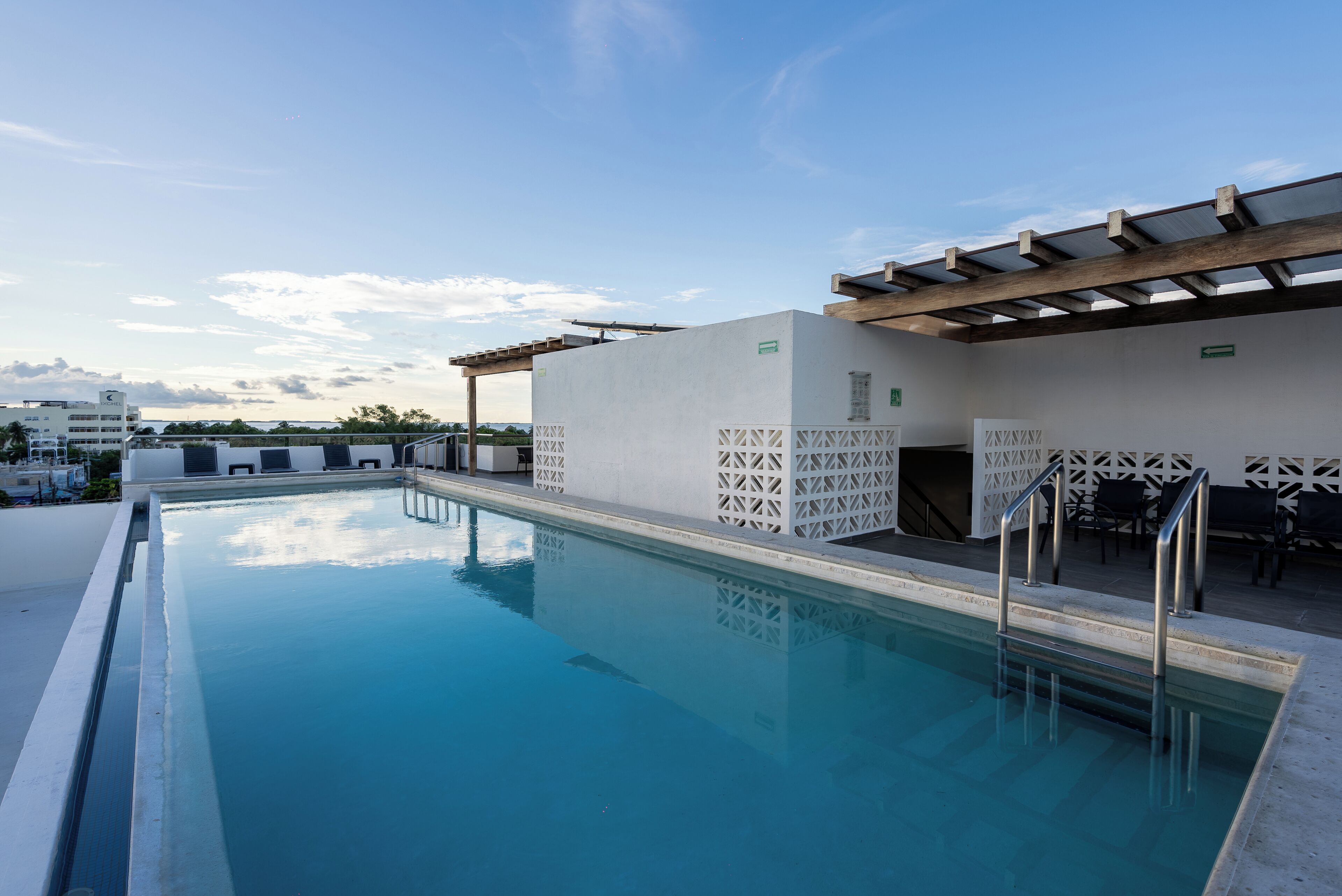 Una piscina con una pérgola, mobiliario de exterior y vistas a la ciudad.