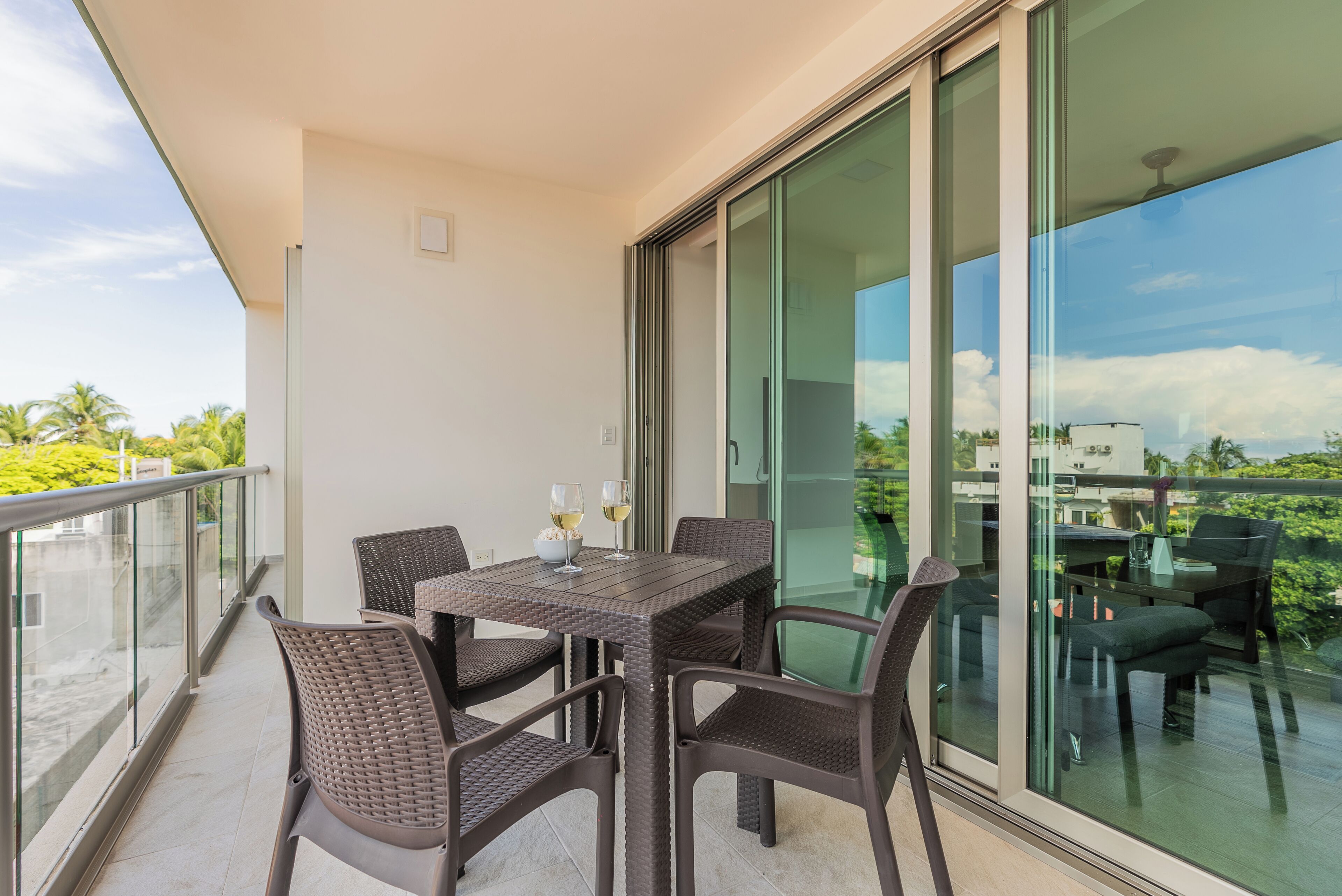 Un balcón con una mesa y sillas, una puerta de cristal y vistas a la ciudad.