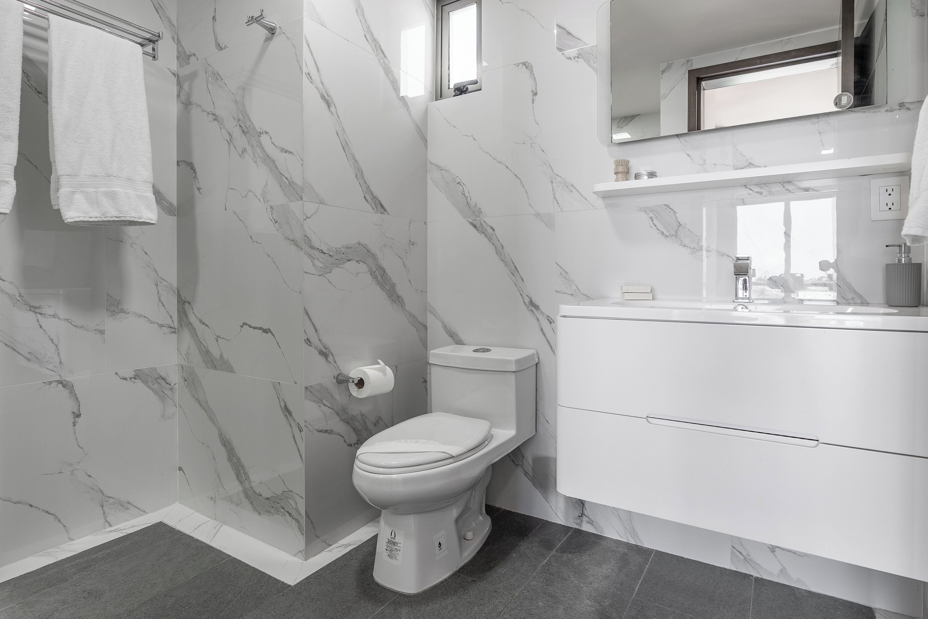 A modern bathroom with a toilet, shower, and vanity.