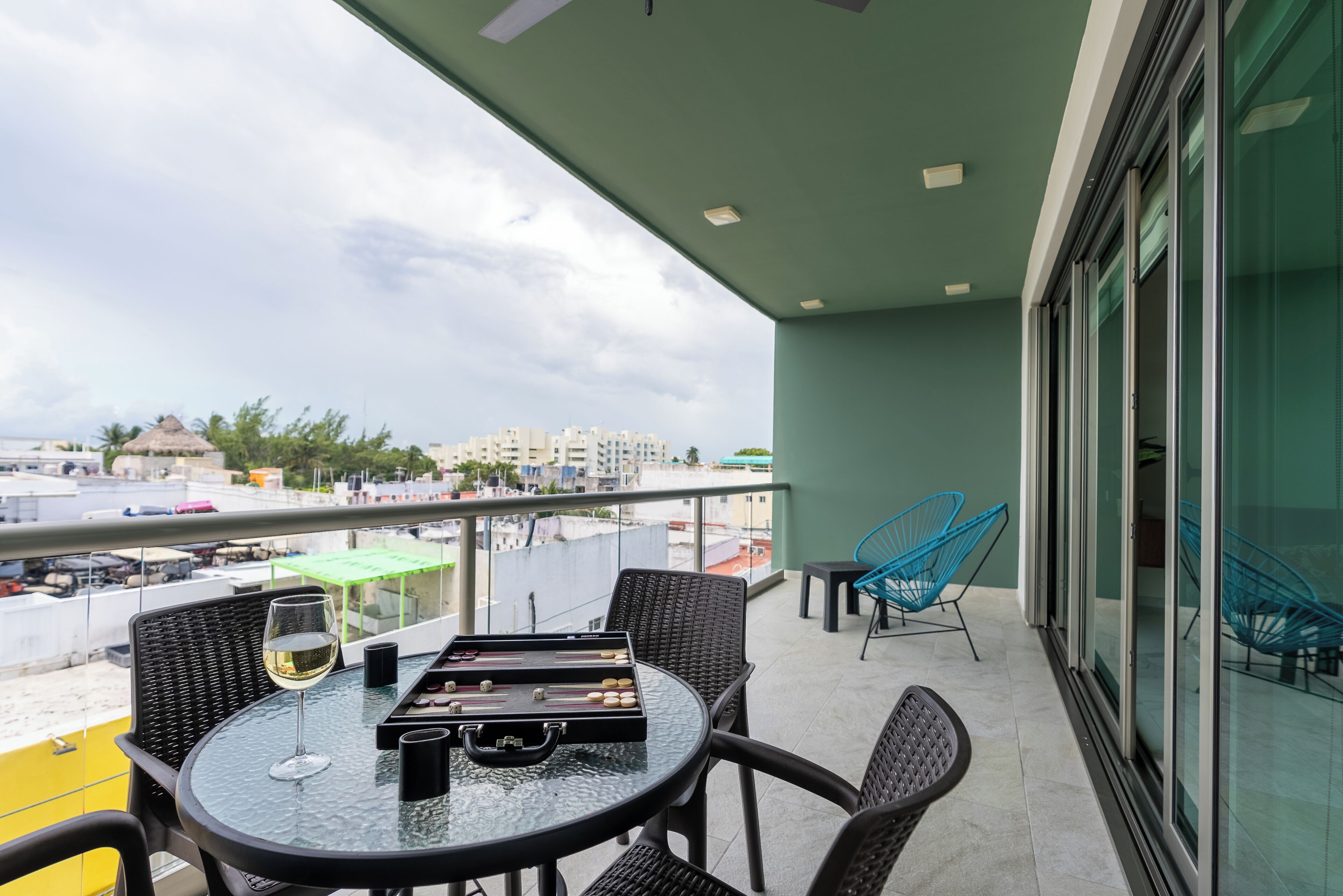 A balcony with a table, chairs, a glass of wine, and a board game.