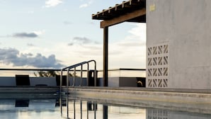 A swimming pool with a concrete structure, a metal handrail, and a clear sky. - La Poza (Isla Mujeres)