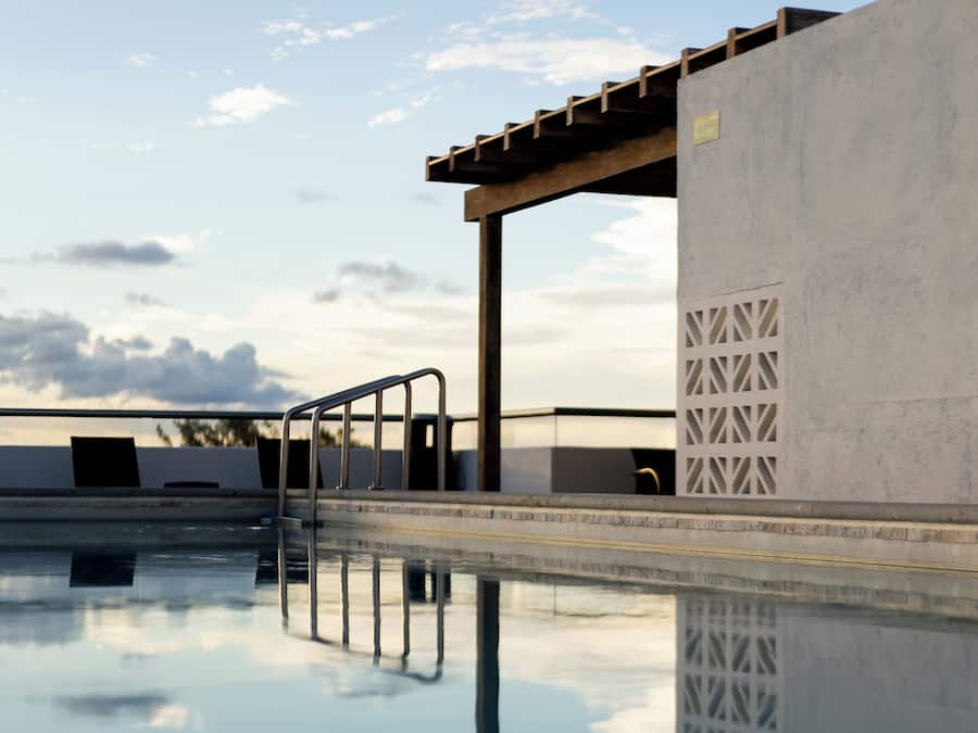 Una piscina con estructura de hormigón, barandilla de metal y cielo despejado.