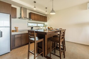Una cocina moderna con armarios de madera, un refrigerador de acero inoxidable, horno empotrado y una isla grande con taburetes de bar.