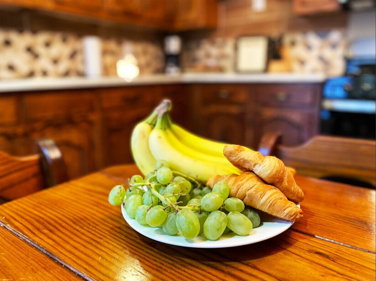 Un plato con uvas y plátanos sobre una mesa de madera en una cocina.