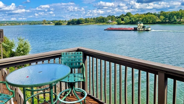 Eine Terrasse mit Tisch und Stühlen mit Blick auf einen Fluss, in der Ferne ein Boot.