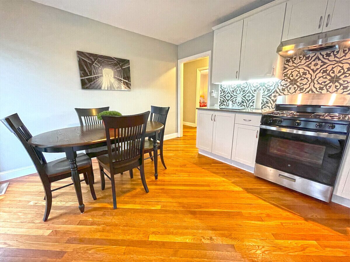 A kitchen with a dining table and chairs, a stove, and cabinets.