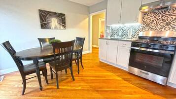 A kitchen with a dining table and chairs, a stove, and cabinets.
