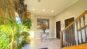 Ein geräumiges Foyer mit Treppe, einem dekorativen Spiegel und einer Blumenvase auf einem runden Tisch.