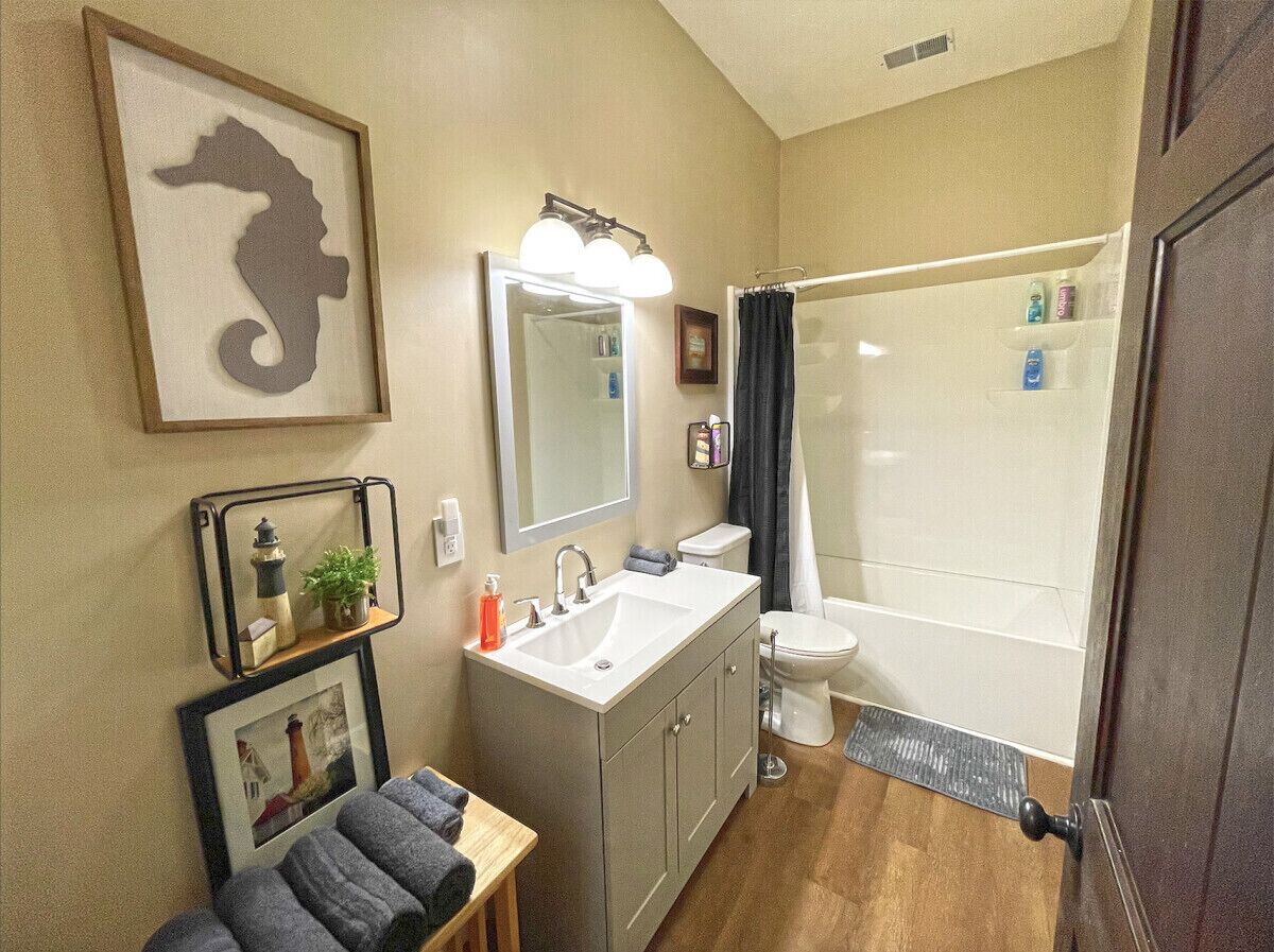 A bathroom with a sink, mirror, toilet, and shower.
