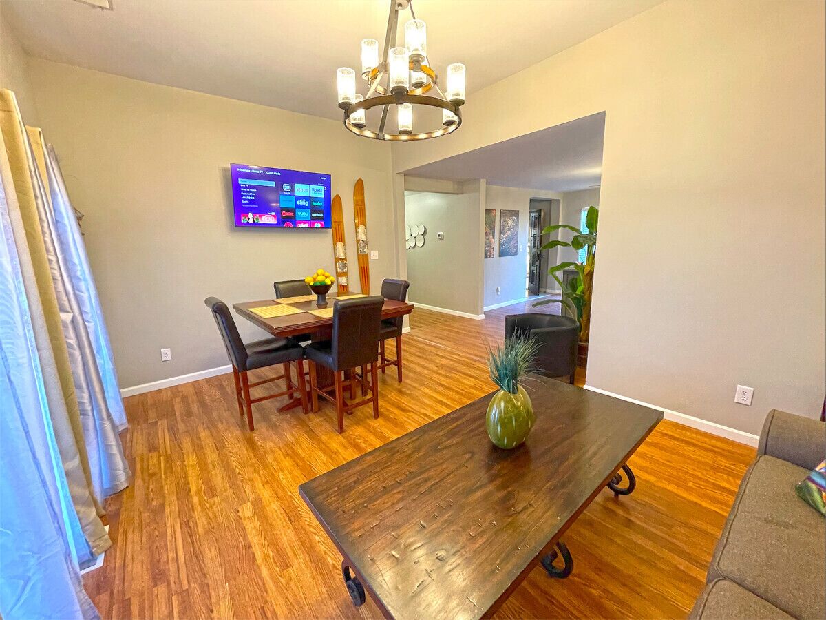 A dining area with a wooden table, chairs, and a television mounted on the wall.
