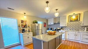 A modern kitchen with a central island, stainless steel appliances, and a patterned backsplash. - Captain's Quarters | One Bed Condo Waterfront on Ohio River (Marietta)