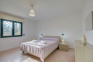 A bedroom with a bed, bedside tables, a nightstand, a window, and a dresser.