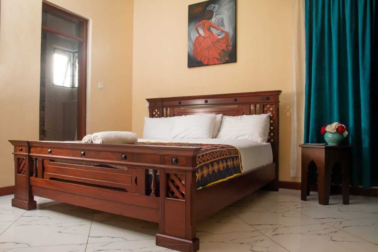 A wooden bed with a headboard, white pillows, and a patterned bedspread.