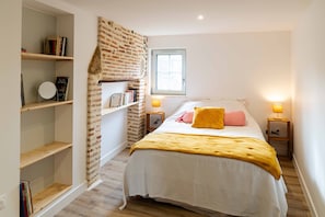 Une chambre à coucher avec un lit, des tables de chevet, une fenêtre et un mur décoré d’un motif en briques.