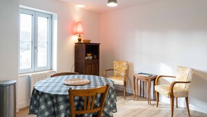 Un coin repas comprenant une table ronde, des chaises, une lampe et un buffet.