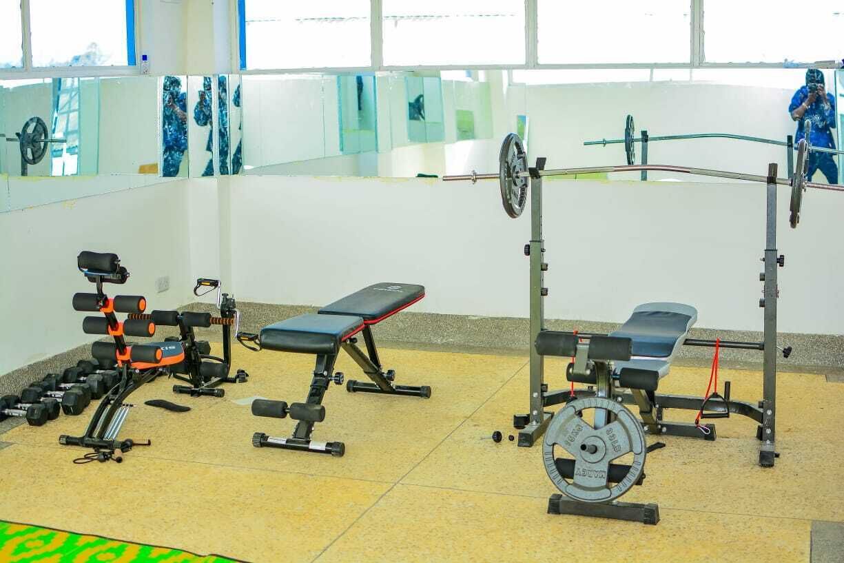 Une salle de sport équipée de divers appareils d’exercice, notamment des haltères, des bancs et des machines de musculation.
