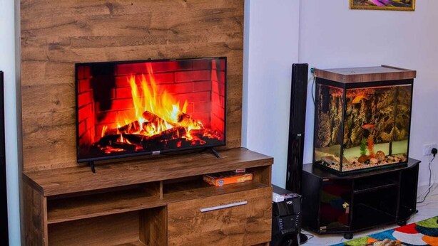 Una sala de estar moderna con chimenea empotrada, un acuario y un televisor de pantalla plana sobre un mueble de madera.