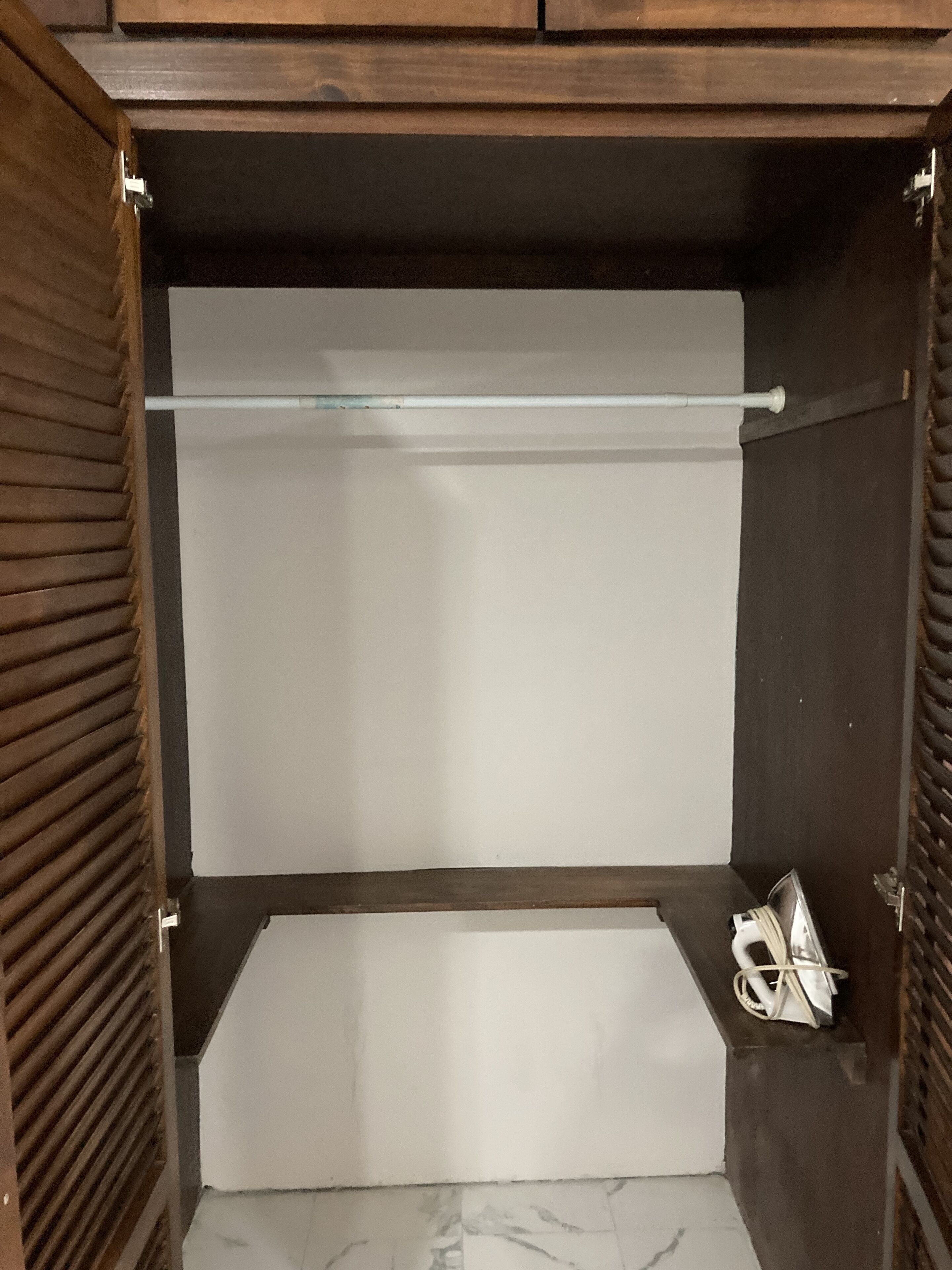 A wardrobe with a hanging rod and a shelf.