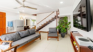 A modern living room with a sofa, chairs, a TV, and a staircase.