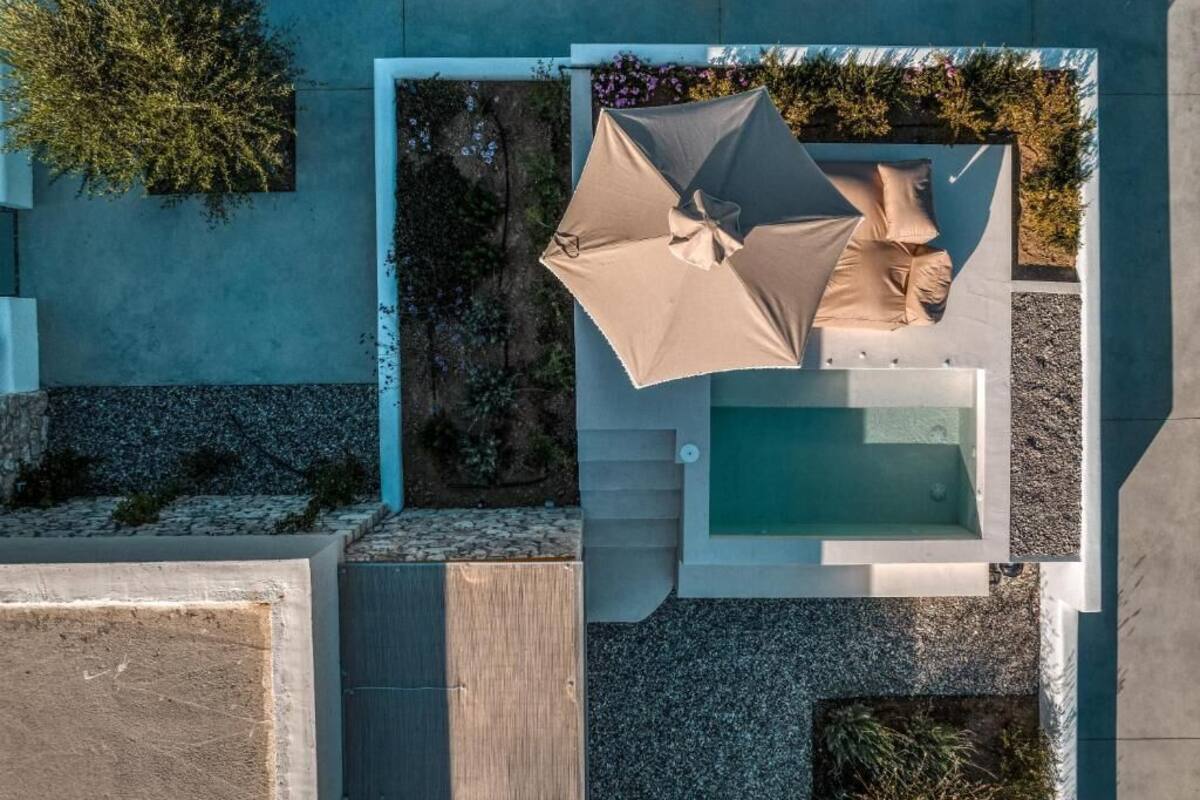 An aerial view of a modern outdoor pool area with a built-in seating area and a small pool.