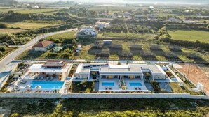 A modern hotel with a swimming pool, surrounded by lush greenery and distant mountains. - Trinity Design Suites (Parga)