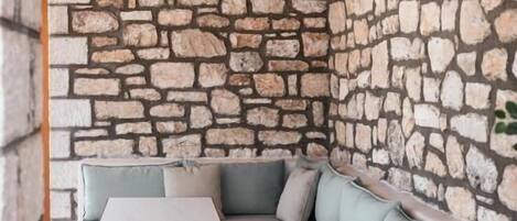 A modern interior with a stone wall, a light blue sofa, and a small table with a white top and brown legs.