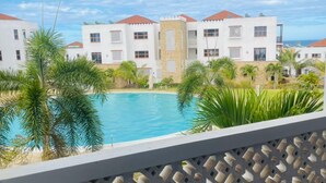 Un espace piscine offrant une vue sur un immeuble doté de nombreux balcons et sur un ciel dégagé.