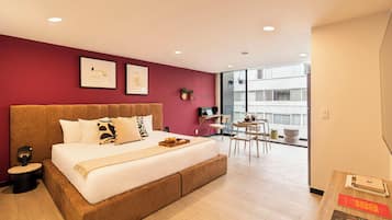 Una habitación de hotel moderna con una cama grande, un escritorio y un balcón con vistas.