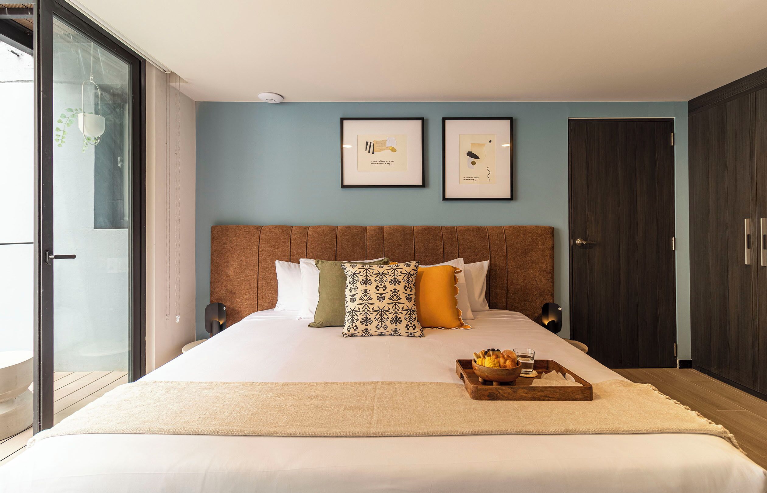 Un dormitorio moderno con una cama grande, un cabecero de madera y dos cuadros enmarcados en la pared.