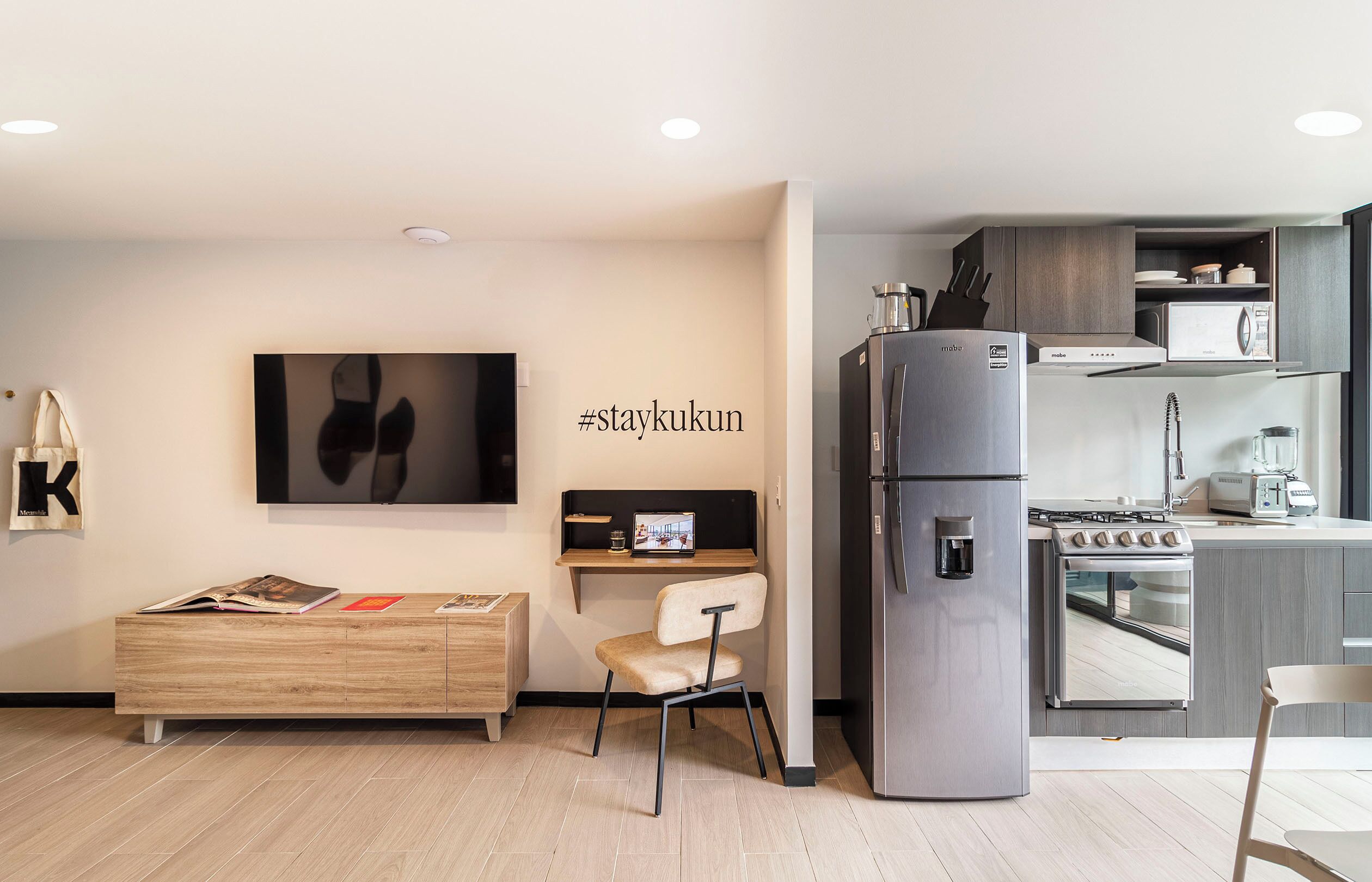 A modern kitchen with a built-in refrigerator, stove, and microwave. There is a wooden dining table and a chair.