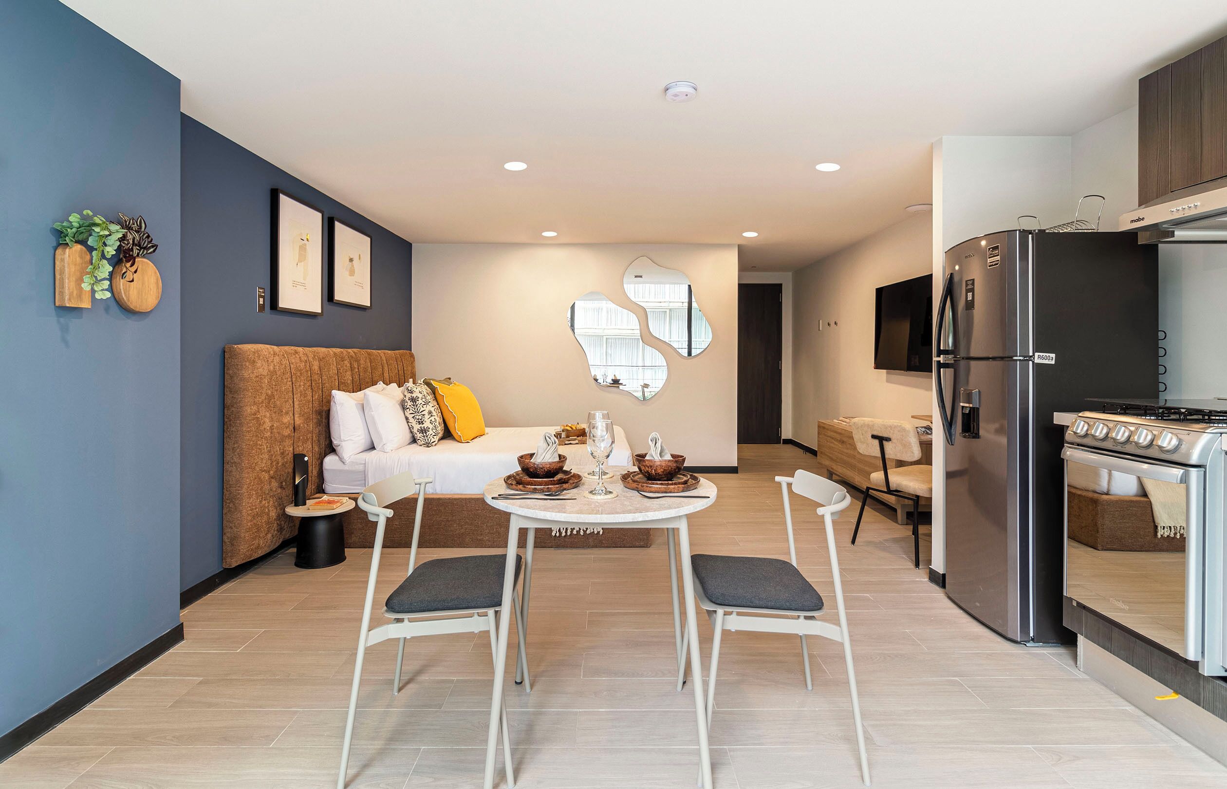 A modern kitchen with a built-in stove, a refrigerator, and a dining area with a table and chairs.
