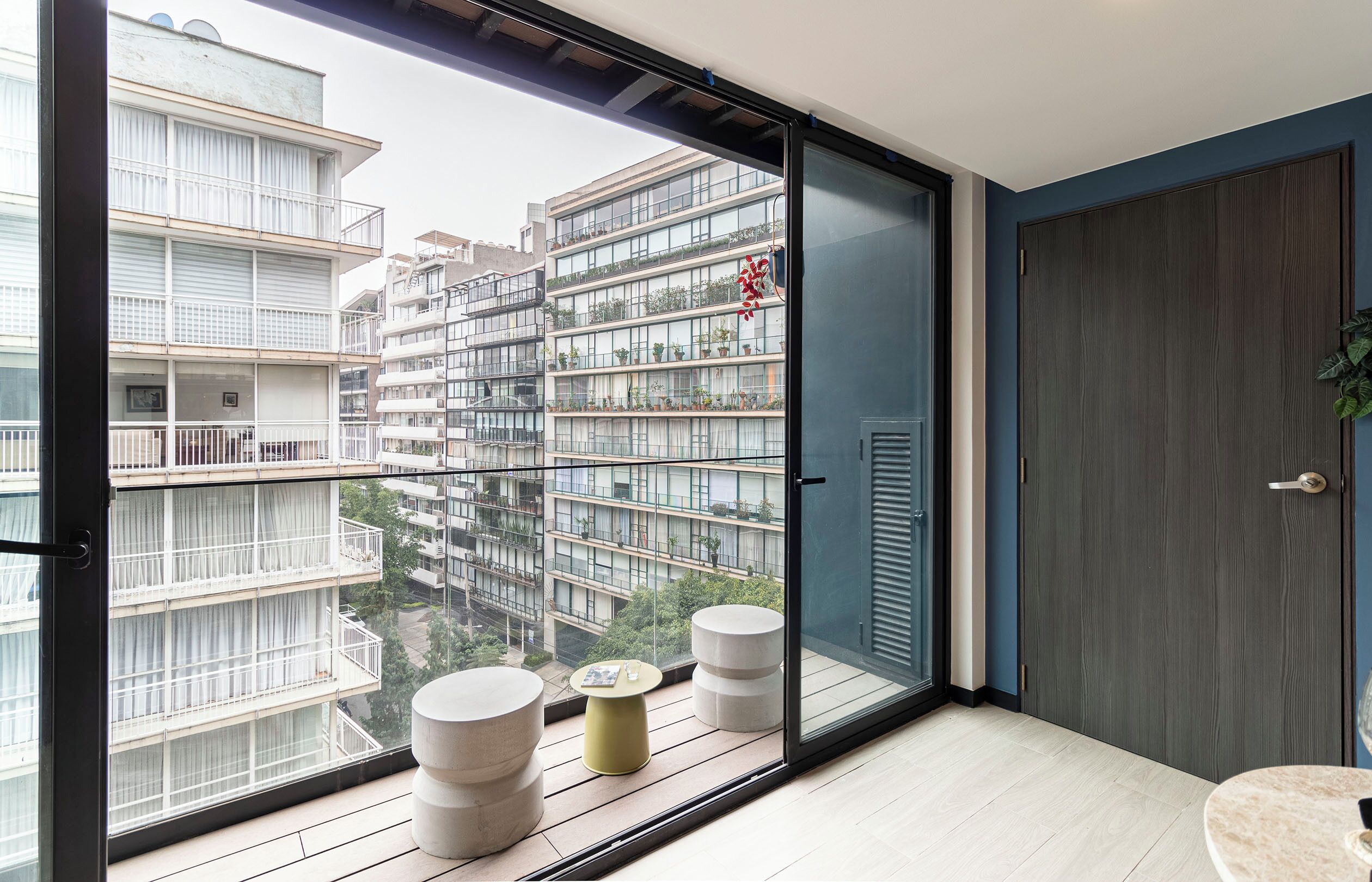 A balcony with a view of a residential building, a sliding glass door, and a small round table with a glass.