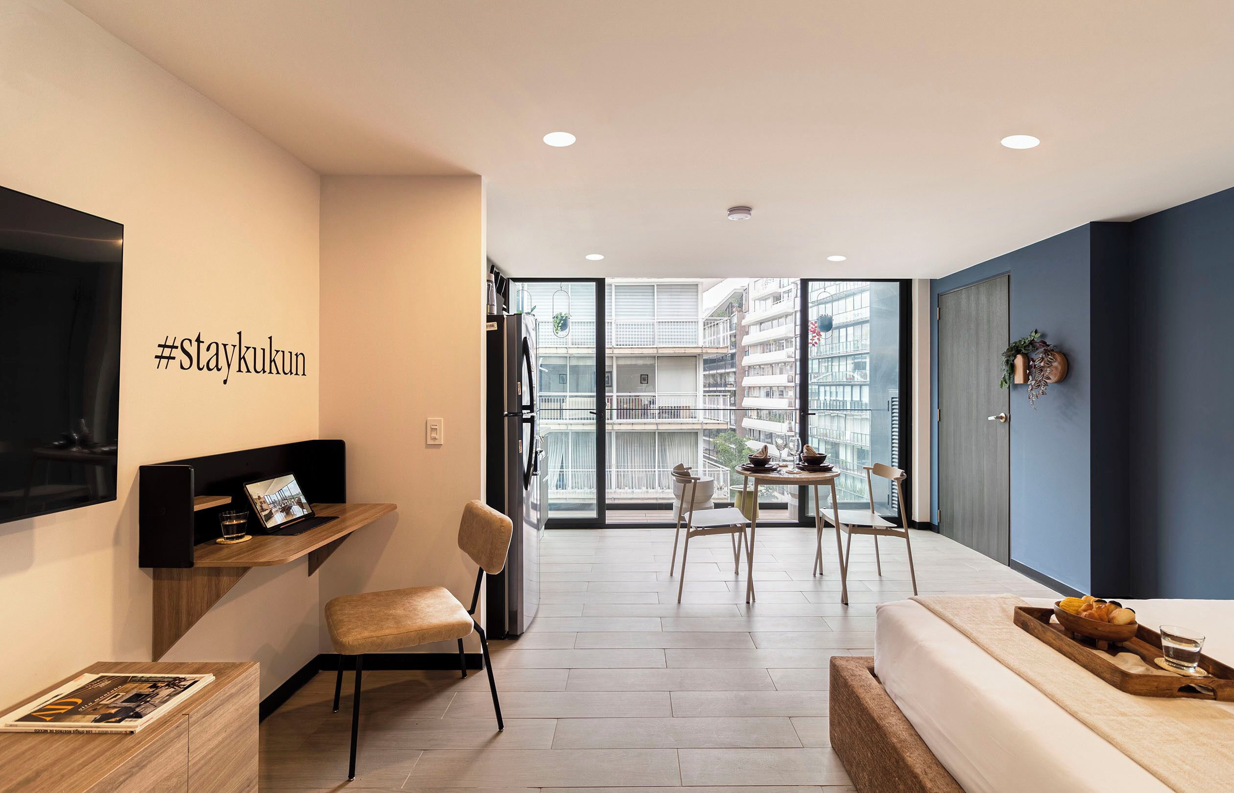 Un apartamento moderno con balcón, comedor y sala de estar con televisor y asientos.
