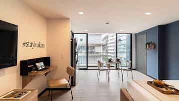 Un apartamento moderno con balcón, comedor y sala de estar con televisor y asientos.