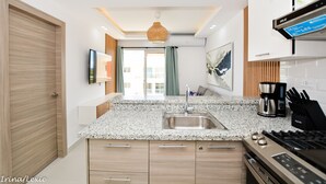 Una cocina moderna con encimera de granito, pileta de acero inoxidable y cafetera.