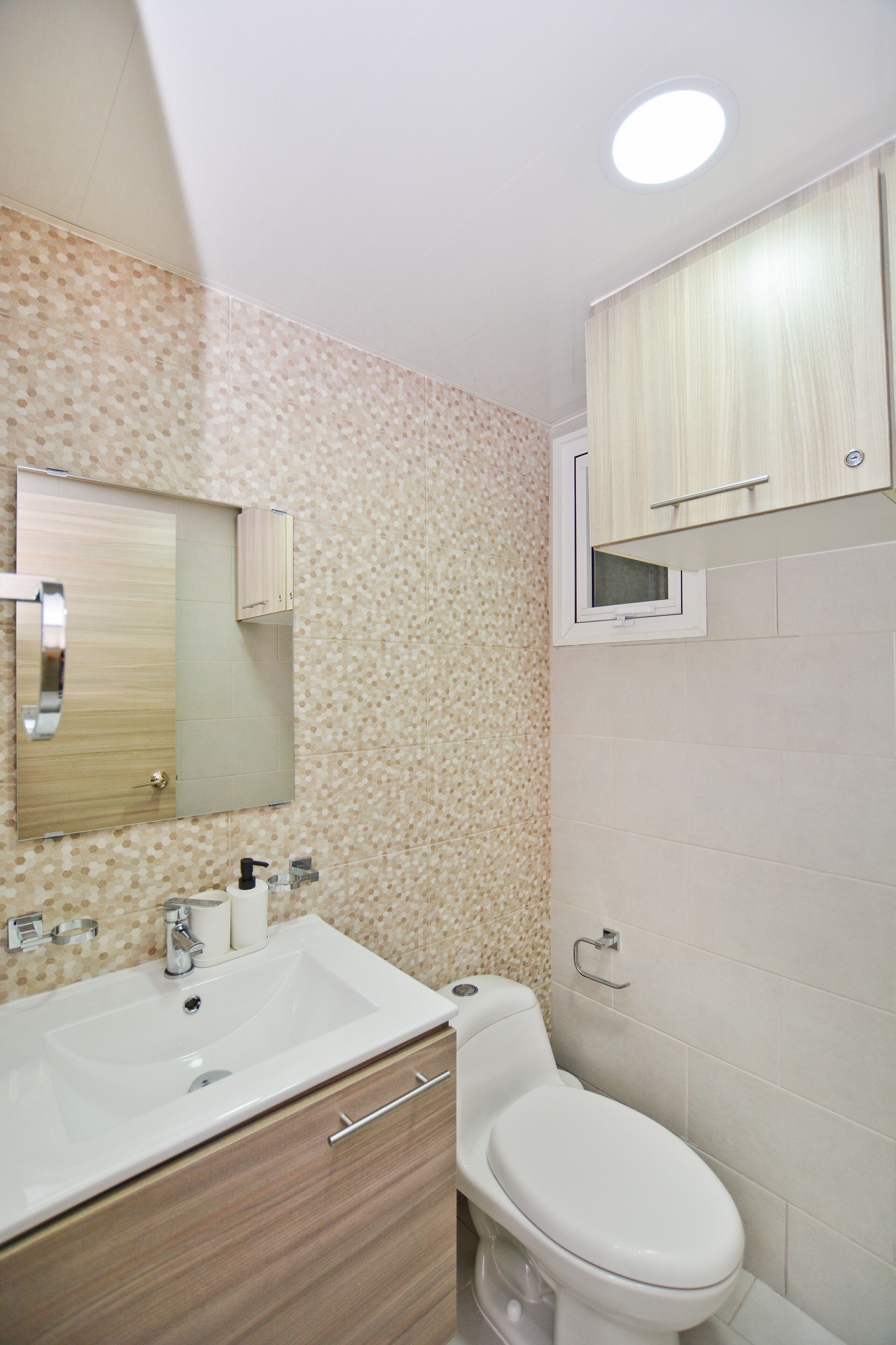 Un baño con lavabo, espejo, inodoro y armario.