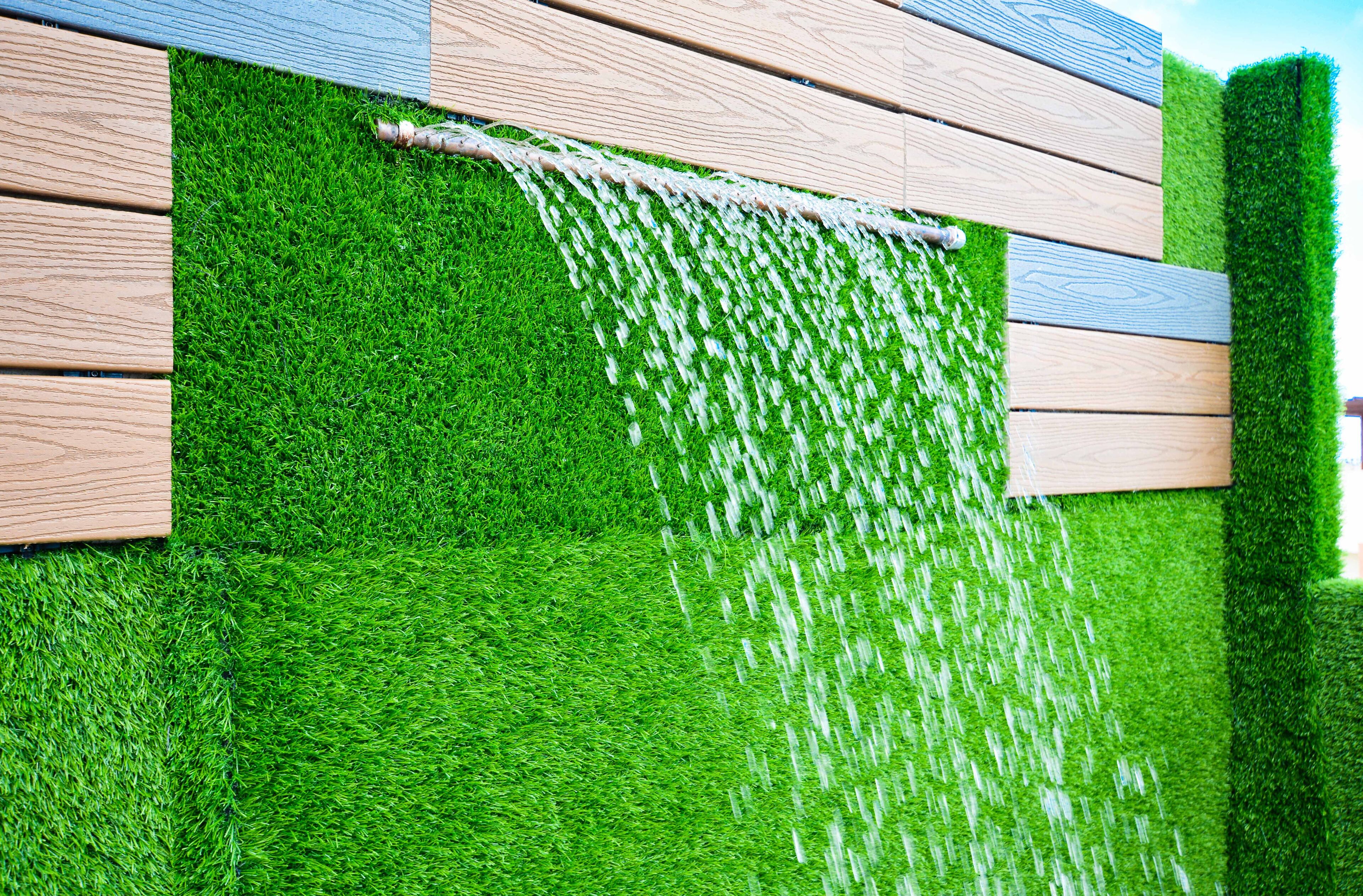 A wall with vertical wooden panels and a green artificial grass surface.