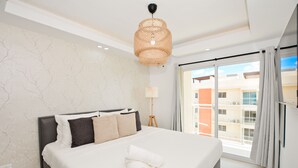 Habitación de hotel con una cama grande, una lámpara de techo y vistas a edificios.