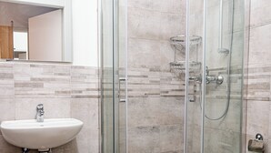 Une salle de bain moderne avec une douche à parois de verre, un lavabo blanc et des toilettes.