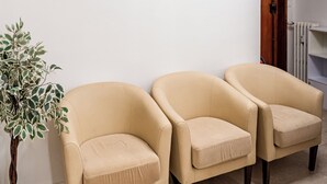Une pièce comprenant trois fauteuils beiges, une plante en pot et un tableau abstrait accroché au mur.