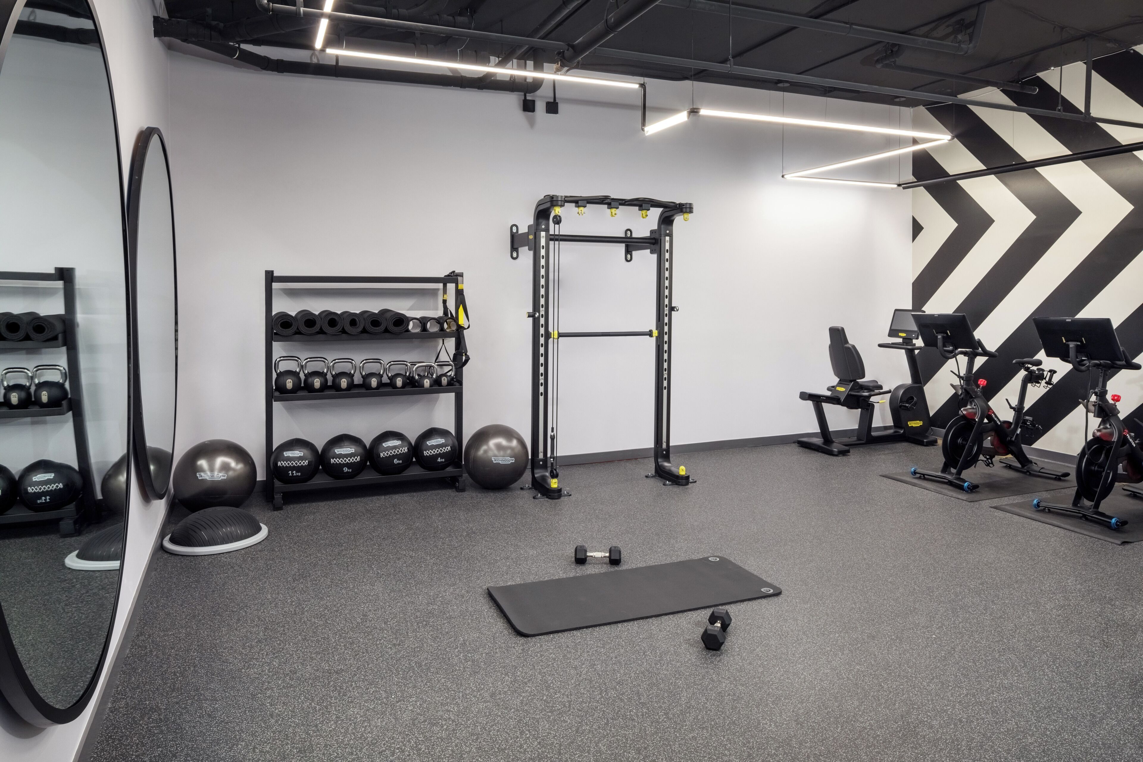 A gym with exercise equipment, dumbbells, and a mirror.