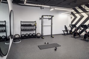 A gym with exercise equipment, dumbbells, and a mirror. - Canopy By Hilton Nashville Downtown The Gulch (Nashville)