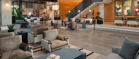 A spacious lobby with seating areas, a staircase, and a reception desk.