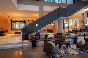 A spacious living area with a modern staircase, a large TV, and a seating area with a coffee table. - Canopy By Hilton Nashville Downtown The Gulch (Nashville)